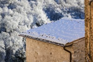 Picturesque winter scene of a snow-covered roof in a cozy village setting.