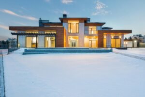 Contemporary luxury villa with modern design illuminated during winter with surrounding snow.