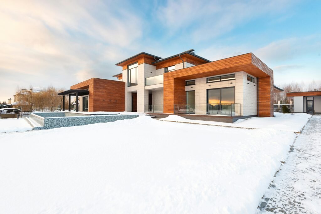 A contemporary house with wooden cladding set in a snowy landscape, showcasing modern architecture.